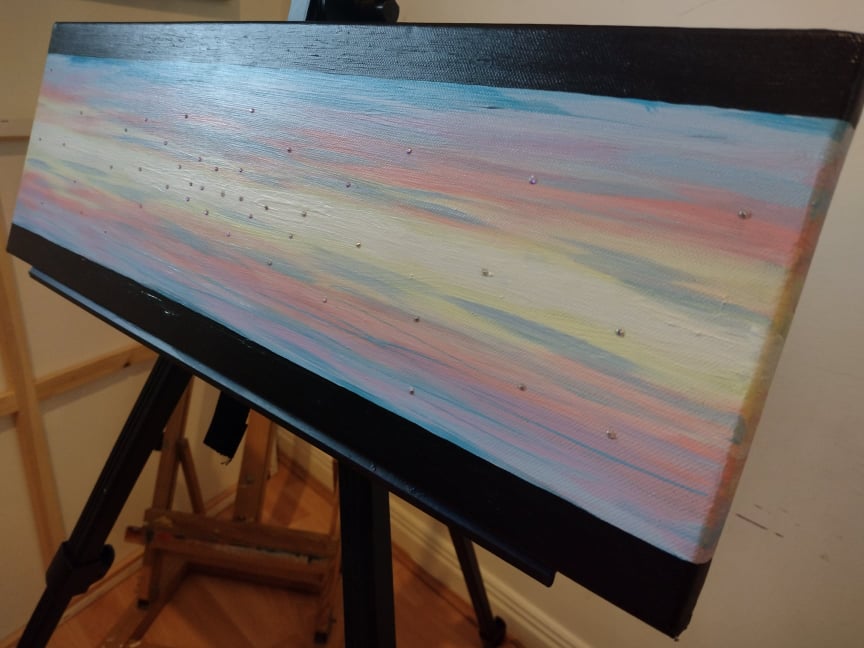Side view photo of 'Heavenly Sky' Original acrylic on canvas painting by Kathryn Mason. Embellished with Swarovski crystals  in abstract style with pastel middle and black top and bottom stripes. 